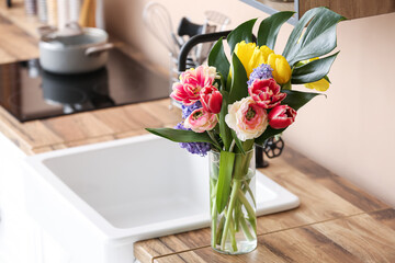 Beautiful bouquet of flowers in vase on kitchen counter near color wall