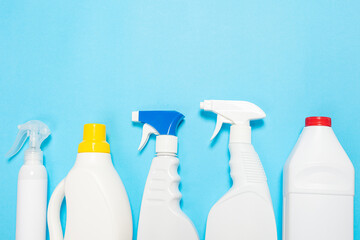 House cleaning supplies on blue background. Row of plastic bottles with cleaning liquid and sponges. Cleaning business, production, shopping and delivery. 