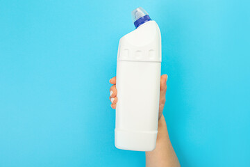 Housewife's hand holds a spray with cleaning agent on a blue background. Detergent for various surfaces in the kitchen, bathroom and other rooms. Close-up. Light pastel blue background. place for text