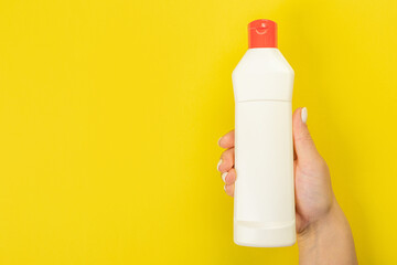Cleaner's hand holding a  chemical spray bottle. Empty space for text or logo on a yellow background. Early spring or regular cleaning. Cleaning and cleaning concept. flat lay