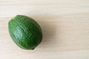 Green avocado on the wooden floor. Fresh avocado on the wooden table.