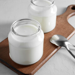 Yogurt, kefir or fermented milk product in glass jars on a wooden board. Healthy food concept