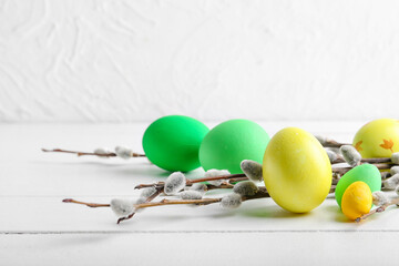 Painted Easter eggs and pussy willow branches on light wooden background