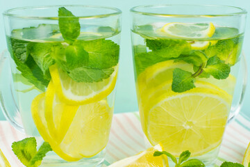 Lemon drink with mint in two glass glasses on a blue background close-up. Detox, lemonade, vitamin C, proper nutrition.
