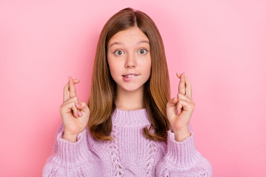 Photo of unsure uncertain girl dressed knitted pullover fingers crossed biting lip isolated pink color background