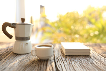 Coffee cup and white moka pot and notebooks with sunlight