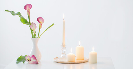 pink calla lily in vase  and burning candles on white background