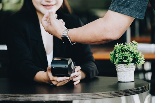 Payment security technology concept and service fees, Employees are holding electronic card machines for customers to use smartwatches to pay via paywave technology.