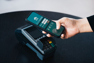 Secure payment technology concept and service charge, customers are using their phone to pay using paywave technology by tapping near the electronic card terminal.