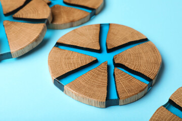Stylish wooden cup coasters on light blue background