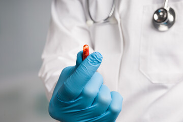 Doctor's hand in medical gloves presents a medicine pill