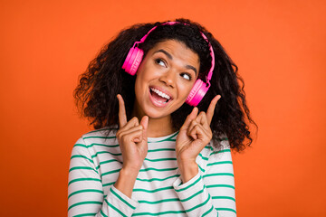 Photo of young lady listen music look up wear earphones shirt isolated on orange background