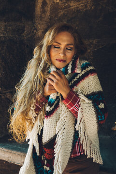 Mature woman enjoys a winter day in a stone cabin with her traditional Mexican poncho (Quechquemitl) next to a wall by the fireplace.