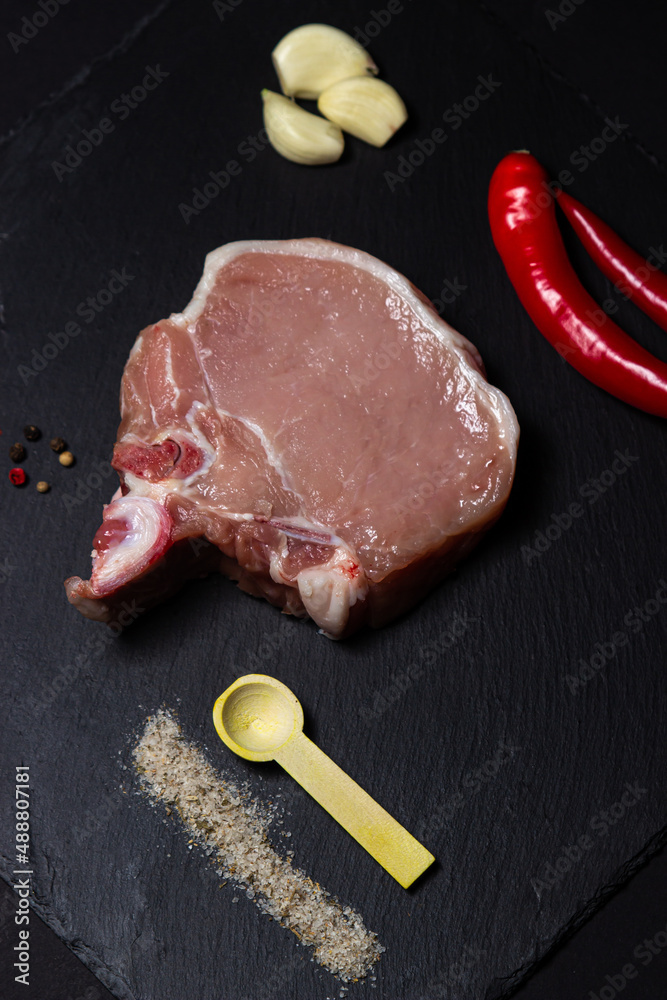 Canvas Prints A piece of pork meat on a black background. Raw meat on a dark dish. Fresh and tender piece of meat.