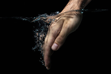 The hand is immersed in water on a black background. Clean and transparent water. hand washing