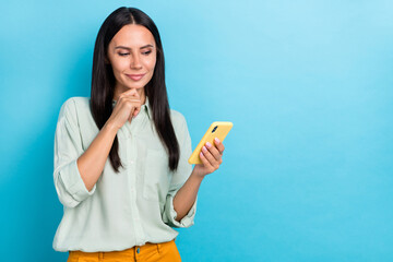 Photo of good looking positive female brainstorming read sms message in cellphone isolated on blue color background