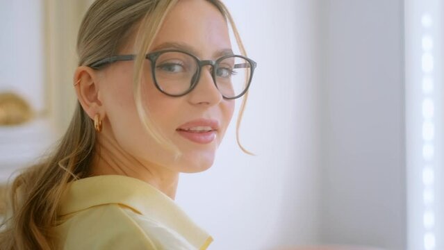 Portrait of happy smiling young attractive caucasian woman in eyeglasses looking on camera in motion.