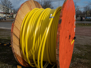 Wooden roller with yellow fiber optic cables for laying data cables at the construction site.