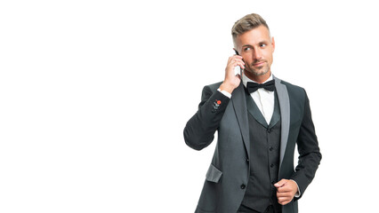 Naklejka premium positive businessman in tuxedo speak on phone isolated on white background