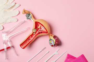 Gynecological examination kit and anatomical uterus model on pink background, flat lay. Space for text - obrazy, fototapety, plakaty