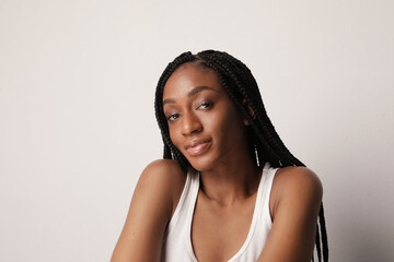 Photo of happy young woman with shining skin and long braids posing over white.