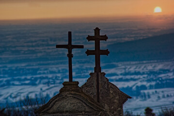 Klasztor Świętego Krzyża na Łyścu ( Łysej Górze) w Górach Świętokrzyskich w paśmie Łysogóry , krzyże nad bramą na tle śnieżnego krajobrazu podświetlonego wschodzącym słońcem .