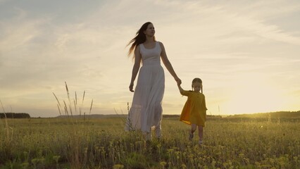 happy family sun. mom child daughter walk at sunset park. little happy kid girl holding mom's hand. evening walk girl with daughter with a parent countryside. day off in nature. childhood dream trip