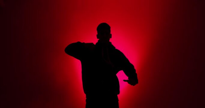 Silhouette of man breakdancing in red light background