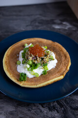 A pancake with sour cream, green onion and red caviar. High quality photo