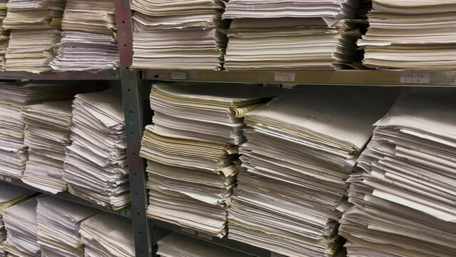 in a file archive there are shelves filled with stacks of paper