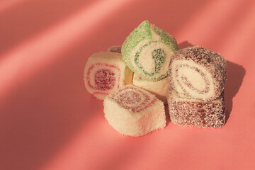 Traditional Turkish delight, rols shape, in coconut flakes , on pink background, sunlight, horizontal, no people,
