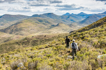 Obraz premium Travel to Lesotho. 2 hikers in the mountains with the shepherds' huts in the distance