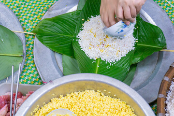 Making chung cake - A traditional food in Tet holiday- Vietnam including green beans, glutinous rice, pork, and pepper wrapped in dong leaves, passed down through generations.