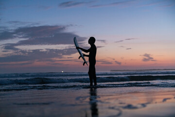 Fototapeta na wymiar 夜明けにサーフィンをする男性