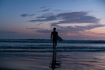夜明けにサーフィンをする男性