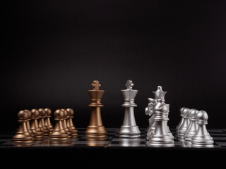 One chess piece stands against a full set of chess pieces. The concept of strategy, planning and decision-making