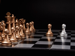 One chess piece stands against a full set of chess pieces. The concept of strategy, planning and decision-making
