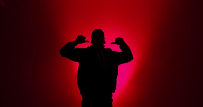 Silhouette of young man breakdancing in red light background