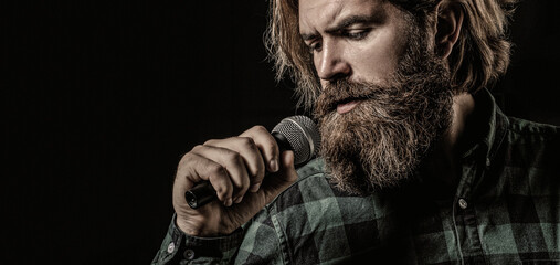 Man singing with microphone. Male singing with a microphones. Bearded man in karaoke sings a song into a microphone. Male attends karaoke. Man with a beard holding a microphone and singing