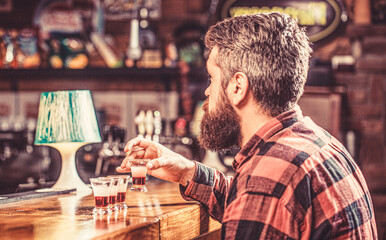 Drinking alcohol into shot glasses in a nightclub or bar. Bearded man shots cocktail. Tequila shots, vodka,whisky, rum. Barman in pub. Tequila shot. Colorful cocktails at the bar