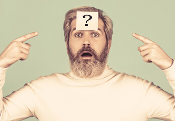 Beard man question mark in head, solution problems. Thinking man with question mark on blue background. Man with question mark on forehead looking up. Paper notes with question marks