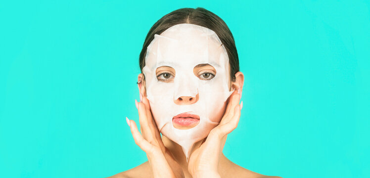 Beautiful woman with beauty mask. Skin care and beauty concept. Moisturizing mask. Anti aging procedure. Woman applying sheet mask on her face, on blue background