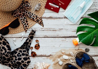 Flat lay travel accessories on light wooden background with copy space: passport, swimsuit, straw hat, glasses and more. Travel or vacation concept from above. Summer background