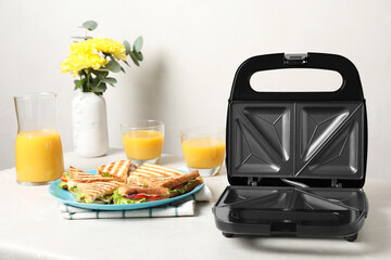 Modern grill maker and sandwiches on white table - obrazy, fototapety, plakaty