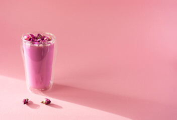 Pink rose milk with rose petals in a double walled glass. Healthy drink moon milk. Copy space.
