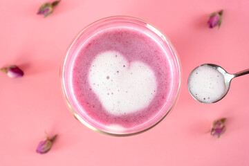 Pink rose milk with rose petals. Adding heart-shaped foam to a glass of moon milk. Healthy drink....
