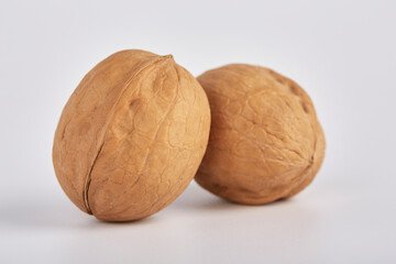 Two large walnuts lie side by side on a white background.