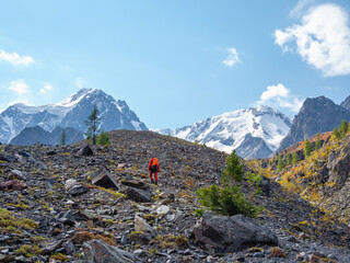 Heavy climbing on a rocky mountain slope. Solo trekking in the mountains. Travel photographer lifestyle, hiking hard track, adventure concept in summer vacation.