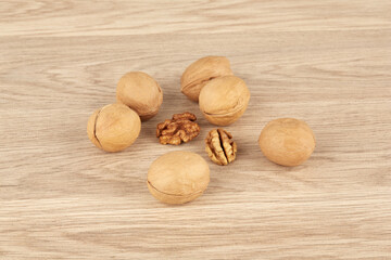 Whole walnuts on a wooden background together with peeled walnuts