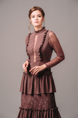 Vintage evening dress. Elegant brown gown. Brunette lady posing in studio. Full length outfit in...